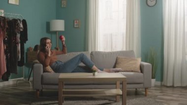 Kırmızı elmalı kadın kanepede uzanıyor ve telefonda konuşuyor.