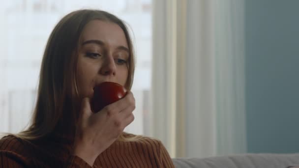 Красивая девушка кусает красное яблоко — стоковое видео