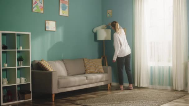 Chica en suéter blanco limpia el polvo de los muebles. Largo plazo — Vídeo de stock