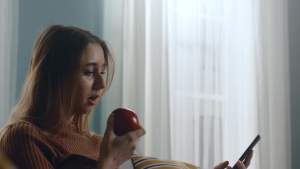 Красивая женщина в профиль кусает красное яблоко — стоковое видео