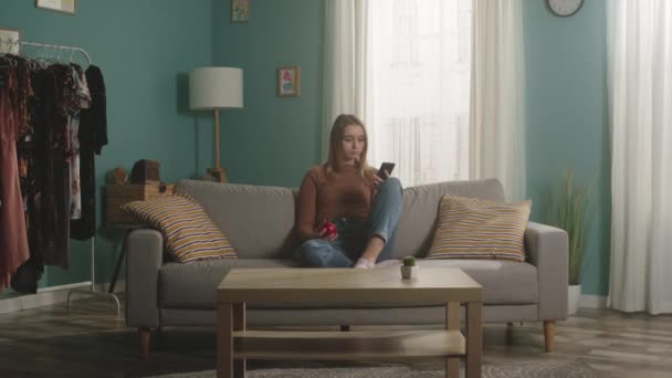 Meisje met rode appel en kijkend naar iets aan de telefoon — Stockvideo