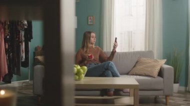 Güzel kadın görüntülü telefonda konuşuyor ve kırmızı elmayı ısırıyor.