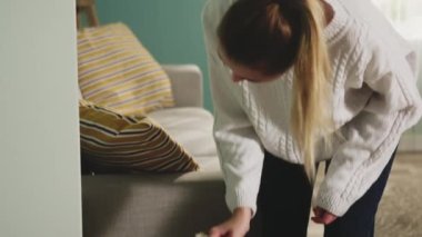 Beyaz kazaklı güzel kadın mobilyaların tozunu sildi..