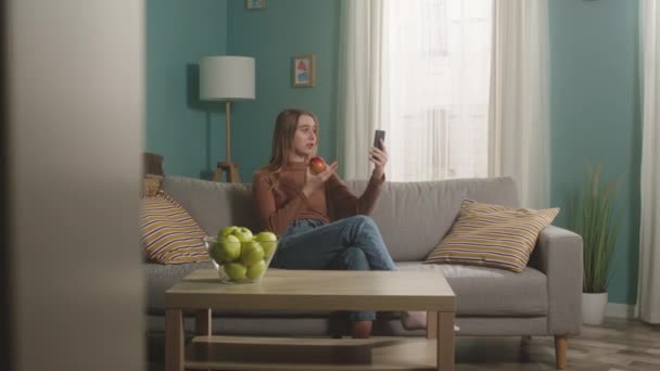 Mooie vrouw praat op video bellen en bijt rode appel — Stockvideo