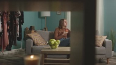 Genç kız görüntülü konuşuyor ve kırmızı elmayı ısırıyor.