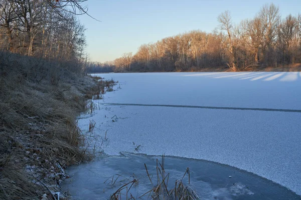 Breath of winter, first ice on the lake, dawn on a frosty morning with frost on the grass, close-up of frost, patterns on the first ice. Winter