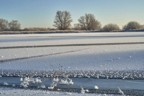 Breath of winter, first ice on the lake, dawn on a frosty morning with frost on the grass, close-up of frost, patterns on the first ice. Winter