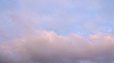 Güzel bir akşam mavi gökyüzü gün batımında, parlak bir ışık parlıyor, güneş ışınlarıyla aydınlanan bulutlar yavaşça gökyüzünde süzülüyor..