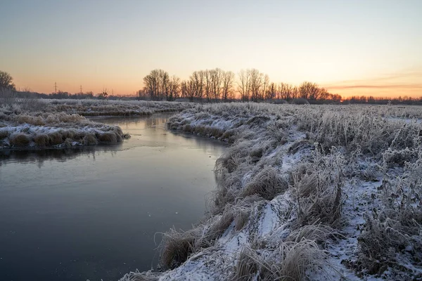 Breath of winter, first ice on the lake, dawn on a frosty morning with frost on the grass, close-up of frost, patterns on the first ice. Winter