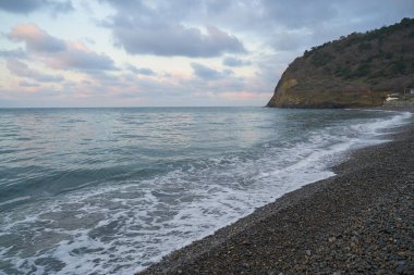 Sakin denizin üzerinde gün doğumu, bulutların arasından bulutların içine, sakin deniz manzarasına, denize doğru, turuncu ışık huzmeleri saçar..