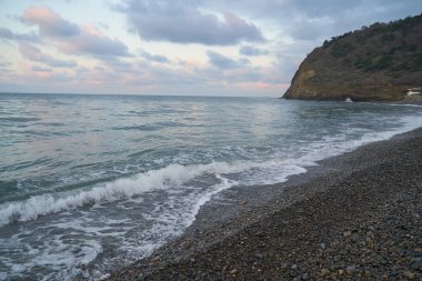 Sakin denizin üzerinde gün doğumu, bulutların arasından bulutların içine, sakin deniz manzarasına, denize doğru, turuncu ışık huzmeleri saçar..