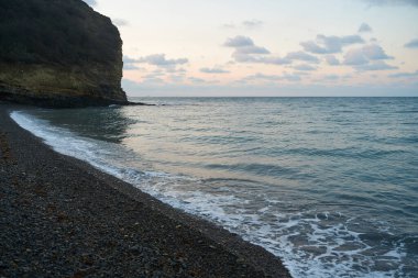 Sakin denizin üzerinde gün doğumu, bulutların arasından bulutların içine, sakin deniz manzarasına, denize doğru, turuncu ışık huzmeleri saçar..