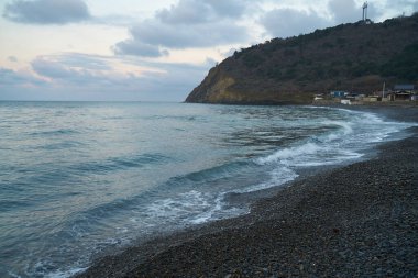 Sakin denizin üzerinde gün doğumu, bulutların arasından bulutların içine, sakin deniz manzarasına, denize doğru, turuncu ışık huzmeleri saçar..