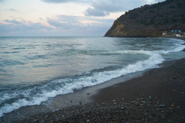 Sakin denizin üzerinde gün doğumu, bulutların arasından bulutların içine, sakin deniz manzarasına, denize doğru, turuncu ışık huzmeleri saçar..