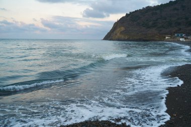 Sakin denizin üzerinde gün doğumu, bulutların arasından bulutların içine, sakin deniz manzarasına, denize doğru, turuncu ışık huzmeleri saçar..