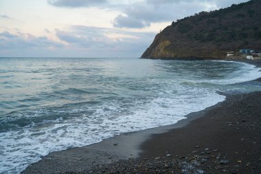 Sakin denizin üzerinde gün doğumu, bulutların arasından bulutların içine, sakin deniz manzarasına, denize doğru, turuncu ışık huzmeleri saçar..