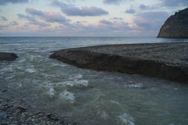 Sakin denizin üzerinde gün doğumu, bulutların arasından bulutların içine, sakin deniz manzarasına, denize doğru, turuncu ışık huzmeleri saçar..