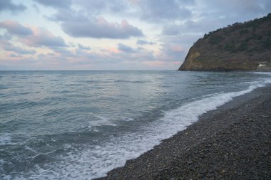 Sakin denizin üzerinde gün doğumu, bulutların arasından bulutların içine, sakin deniz manzarasına, denize doğru, turuncu ışık huzmeleri saçar..