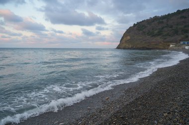 Sakin denizin üzerinde gün doğumu, bulutların arasından bulutların içine, sakin deniz manzarasına, denize doğru, turuncu ışık huzmeleri saçar..