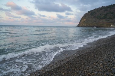 Sakin denizin üzerinde gün doğumu, bulutların arasından bulutların içine, sakin deniz manzarasına, denize doğru, turuncu ışık huzmeleri saçar..