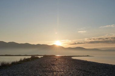 Sakin denizin üzerinde gün doğumu, bulutların arasından bulutların içine, sakin deniz manzarasına, denize doğru, turuncu ışık huzmeleri saçar..