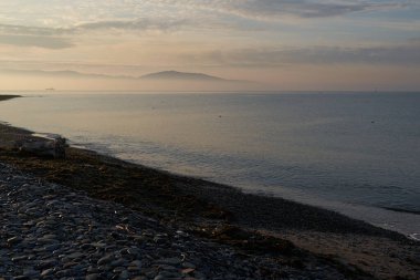 Sakin denizin üzerinde gün doğumu, bulutların arasından bulutların içine, sakin deniz manzarasına, denize doğru, turuncu ışık huzmeleri saçar..