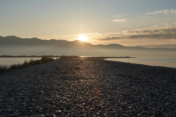 Sakin denizin üzerinde gün doğumu, bulutların arasından bulutların içine, sakin deniz manzarasına, denize doğru, turuncu ışık huzmeleri saçar..