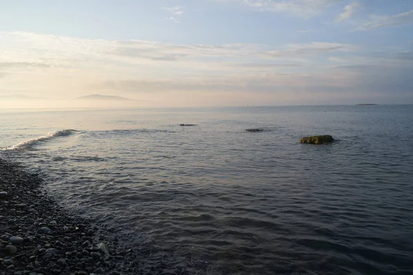 Sakin denizin üzerinde gün doğumu, bulutların arasından bulutların içine, sakin deniz manzarasına, denize doğru, turuncu ışık huzmeleri saçar..