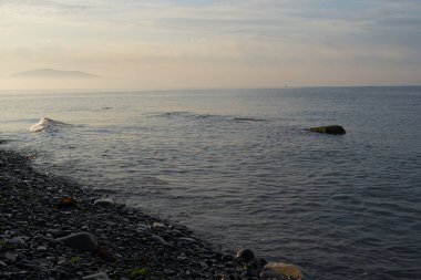 Sakin denizin üzerinde gün doğumu, bulutların arasından bulutların içine, sakin deniz manzarasına, denize doğru, turuncu ışık huzmeleri saçar..