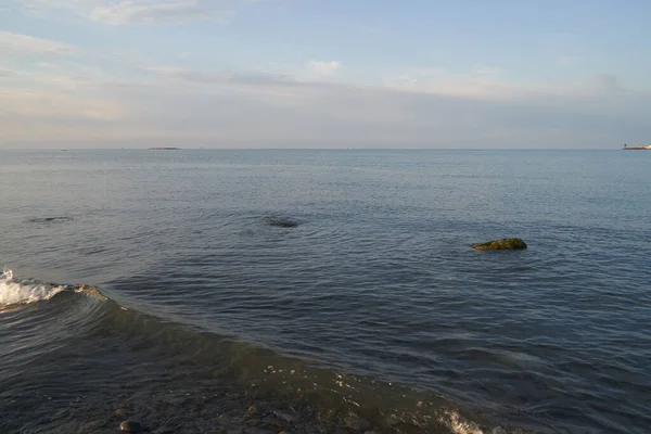 El amanecer sobre el mar en calma proyecta rayos de luz naranja en el aire mientras el sol poniente penetra a través de las nubes en el pintoresco paisaje marino tranquilo, el mar. — Foto de Stock