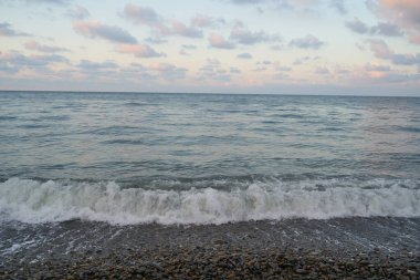 Sakin denizin üzerinde gün doğumu, bulutların arasından bulutların içine, sakin deniz manzarasına, denize doğru, turuncu ışık huzmeleri saçar..