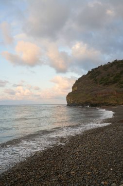 Sakin denizin üzerinde gün doğumu, bulutların arasından bulutların içine, sakin deniz manzarasına, denize doğru, turuncu ışık huzmeleri saçar..