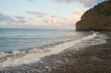 Sakin denizin üzerinde gün doğumu, bulutların arasından bulutların içine, sakin deniz manzarasına, denize doğru, turuncu ışık huzmeleri saçar..