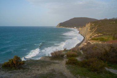 Sakin denizin üzerinde gün doğumu, bulutların arasından bulutların içine, sakin deniz manzarasına, denize doğru, turuncu ışık huzmeleri saçar..