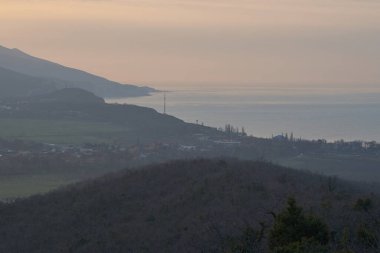 Sakin denizin üzerinde gün doğumu, bulutların arasından bulutların içine, sakin deniz manzarasına, denize doğru, turuncu ışık huzmeleri saçar..