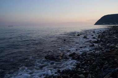 Sakin denizin üzerinde gün doğumu, bulutların arasından bulutların içine, sakin deniz manzarasına, denize doğru, turuncu ışık huzmeleri saçar..