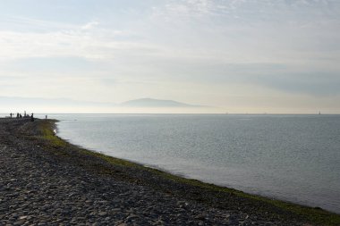 Sakin denizin üzerinde gün doğumu, bulutların arasından bulutların içine, sakin deniz manzarasına, denize doğru, turuncu ışık huzmeleri saçar..