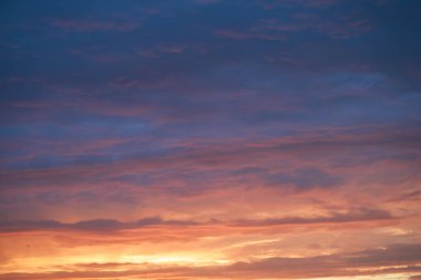Gün batımında parlayan parlak ışık bulutlarıyla güzel bir akşam masmavi gökyüzü. Gün batımında sıcak bir yaz akşamı. Parlak gün batımı.