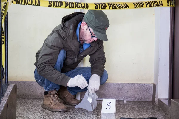 犯罪現場 警察は殺人者が使用した銃を拒否し 殺人の証拠として取り上げ ゴム手袋をして証拠としてバッグの中に入る ロイヤリティフリーのストック画像
