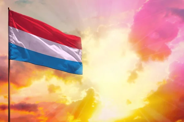 Fluttering Luxembourg flag in left top corner mockup with the place for your information on beautiful colorful sunset or sunrise background.