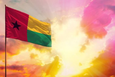 Fluttering Guinea-Bissau flag in left top corner mockup with the place for your information on beautiful colorful sunset or sunrise background.