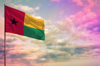 Renkli bulutlu gökyüzü arkaplanı üzerine yazdığınız metin için yer ile titreşen Gine-Bissau bayrağı modeli.