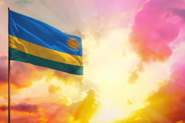 Fluttering Rwanda flag in left top corner mockup with the place for your information on beautiful colorful sunset or sunrise background.