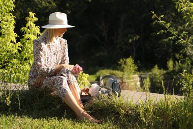 Çiçekli güzel yeşil bir parkta oturan bir kadın.