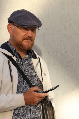 Dışarıda telefonla ciddi ciddi bakan bir adam var.