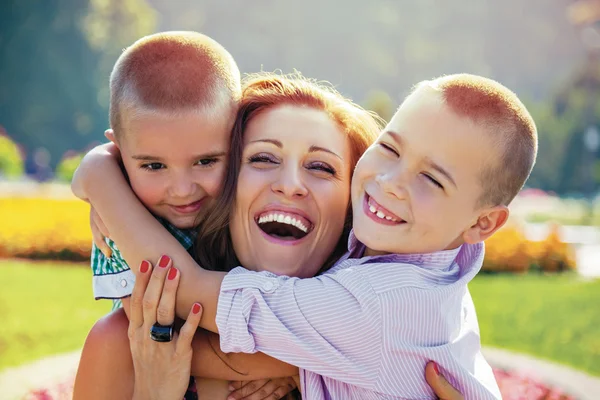 Šťastná matka synů obejmout parku letní — Stock fotografie