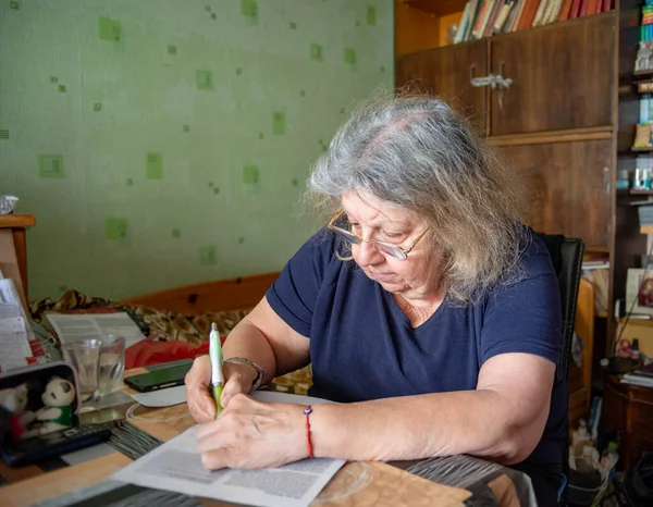 Пожилая леди подписывает бумаги в своей спальне — стоковое фото
