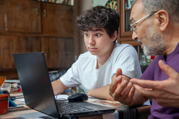 Avô está explicando ao seu neto surpreso uma lição sobre laptop em casa — Fotografia de Stock