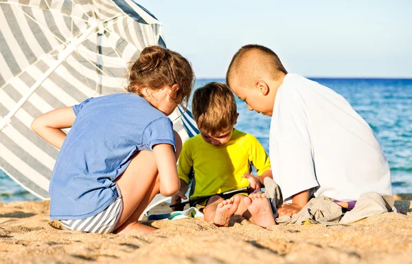 Niños juego tableta de playa —  Fotos de Stock