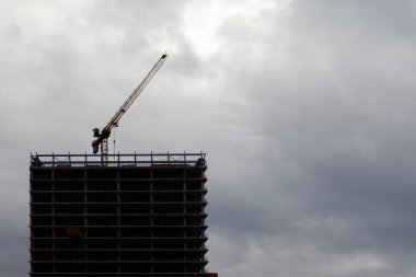 Bulutlu gökyüzünde vinç olan inşaat silueti.
